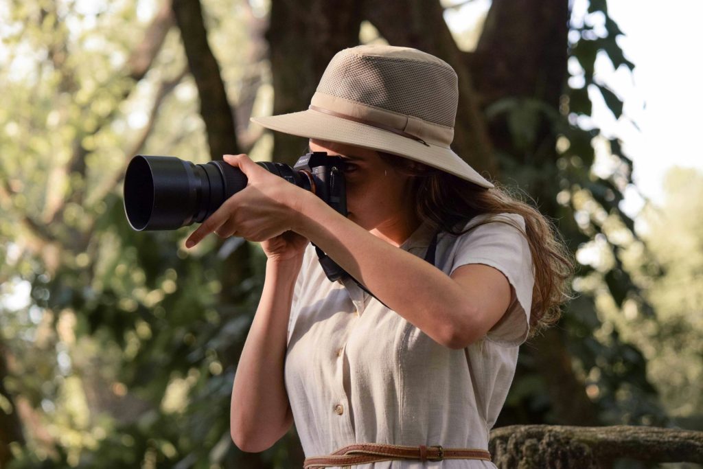 woman in white button up shirt holding black dslr camera