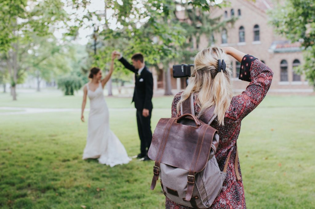 woman in red and black floral dress carrying black leather shoulder bag